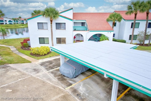 exterior space with a water view, a front yard, and a tiled roof