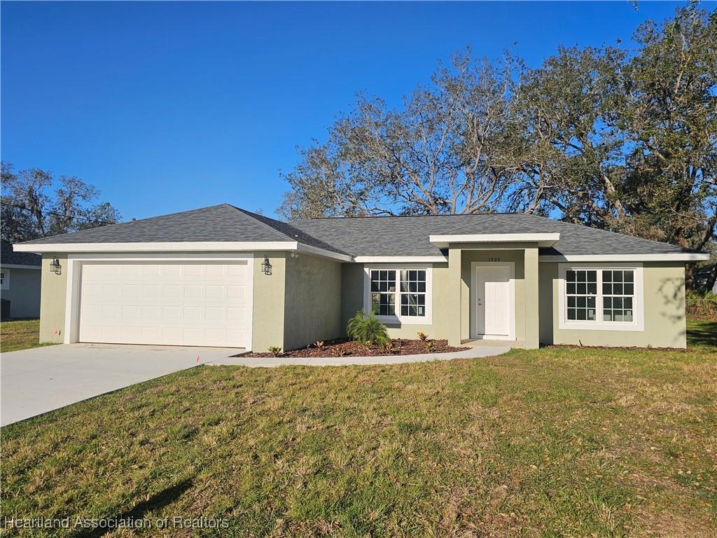 ranch-style home with stucco siding, an attached garage, concrete driveway, and a front lawn