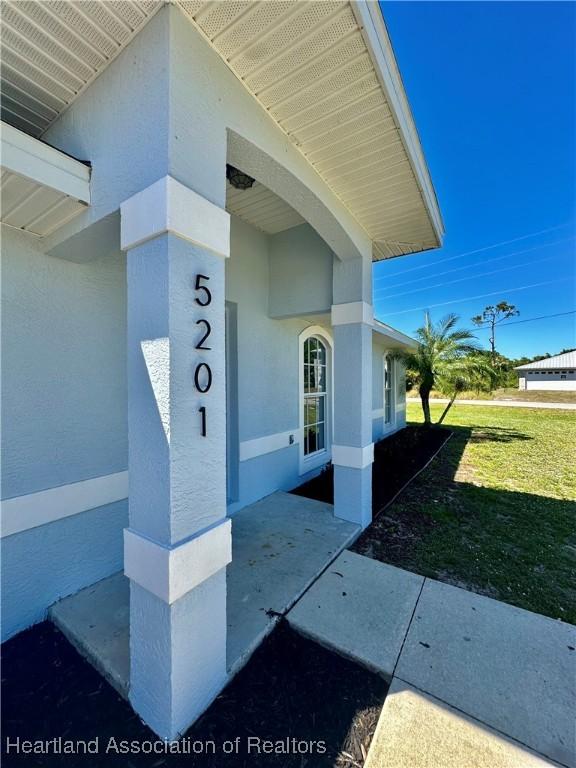 entrance to property featuring stucco siding and a lawn