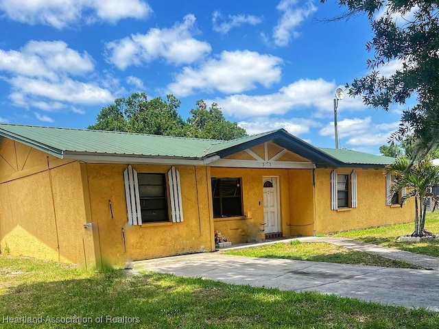 315 Indiana Ave, Wauchula, FL 33873 - view of front of house with metal roof, a front yard, and stucco siding