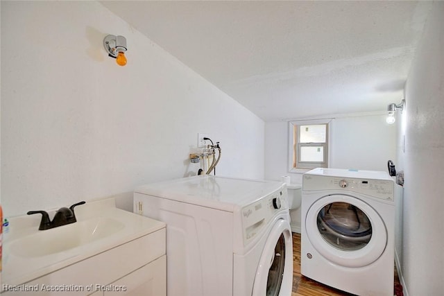 washroom with washing machine and clothes dryer, sink, wood-type flooring, and a textured ceiling