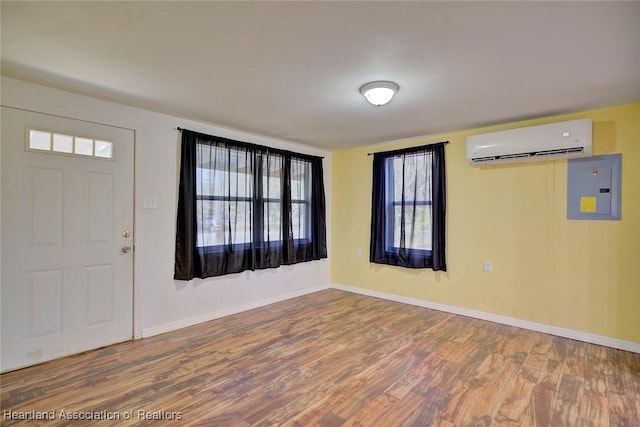 foyer entrance featuring wood-type flooring, electric panel, and an AC wall unit