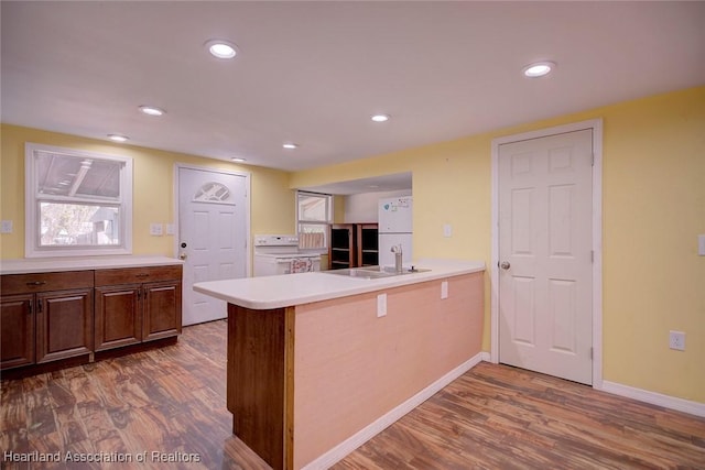 kitchen with kitchen peninsula, dark hardwood / wood-style flooring, sink, white refrigerator, and range