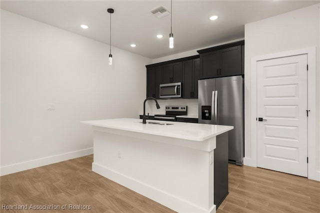 5243 Cortez Blvd, Sebring, FL 33872 - kitchen with stainless steel appliances, a sink, dark cabinetry, light countertops, and an island with sink