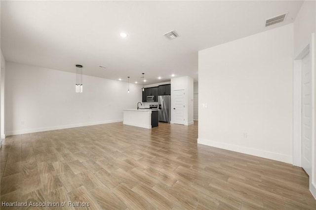 5243 Cortez Blvd, Sebring, FL 33872 - unfurnished living room featuring recessed lighting, light wood finished floors, baseboards, and a sink