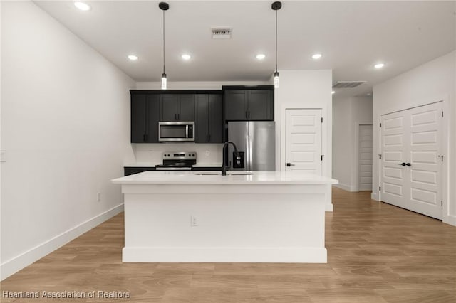 5243 Cortez Blvd, Sebring, FL 33872 - kitchen with appliances with stainless steel finishes, dark cabinetry, light countertops, a kitchen island with sink, and baseboards