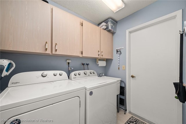 washroom featuring washer and dryer, cabinets, and a textured ceiling