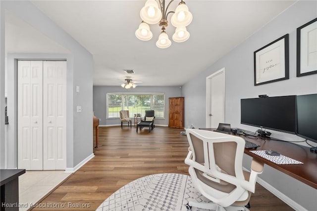 office with hardwood / wood-style floors and ceiling fan with notable chandelier