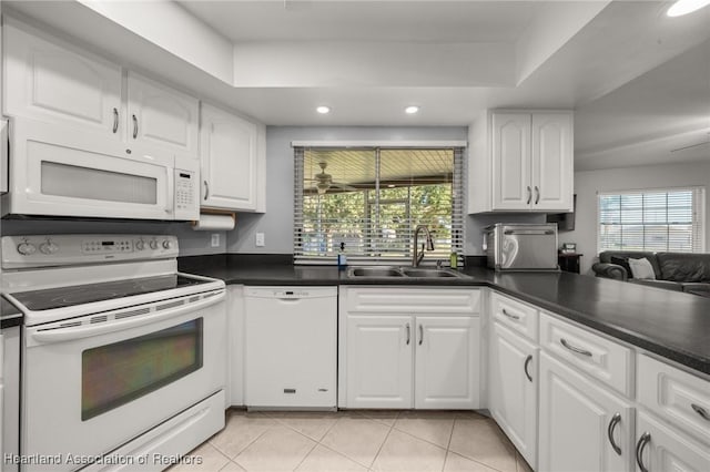 kitchen with white appliances, a raised ceiling, sink, white cabinetry, and light tile patterned flooring