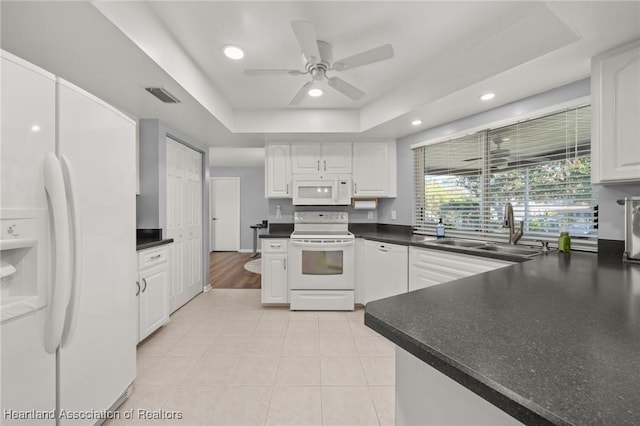 kitchen featuring white cabinetry, sink, ceiling fan, white appliances, and a tray ceiling