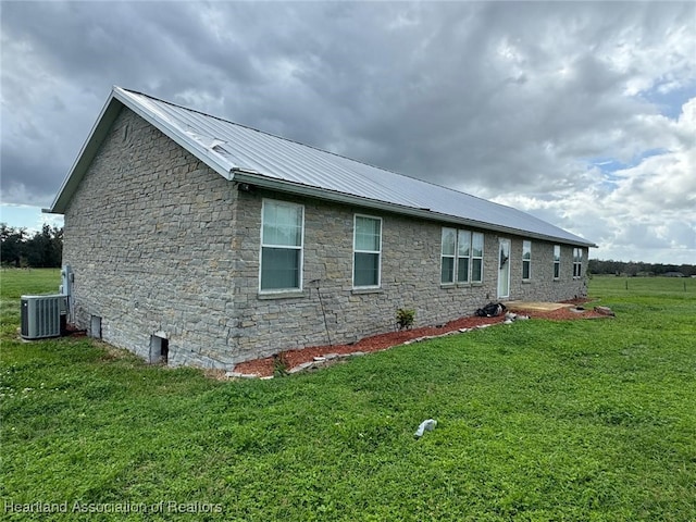 view of side of home featuring cooling unit and a lawn