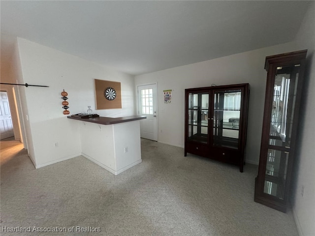 kitchen with carpet flooring, a kitchen breakfast bar, and kitchen peninsula