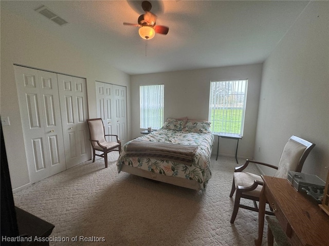 bedroom featuring carpet, ceiling fan, and multiple closets