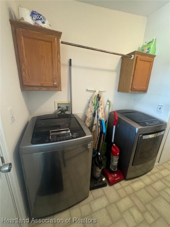 clothes washing area featuring washer and clothes dryer and cabinets