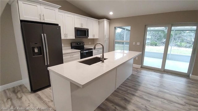 kitchen featuring stainless steel fridge, electric range, white cabinetry, and a kitchen island with sink