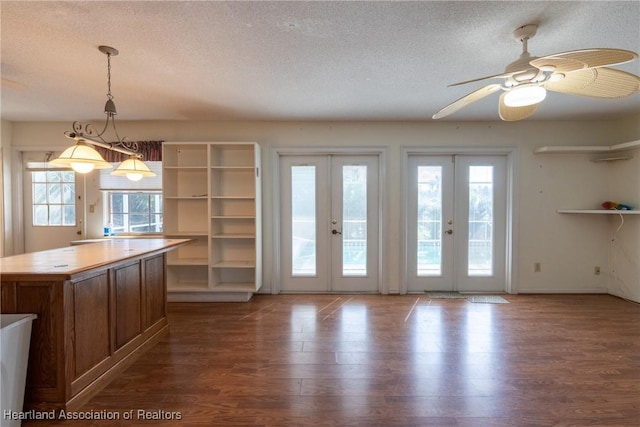 interior space featuring ceiling fan, dark hardwood / wood-style floors, pendant lighting, a textured ceiling, and french doors