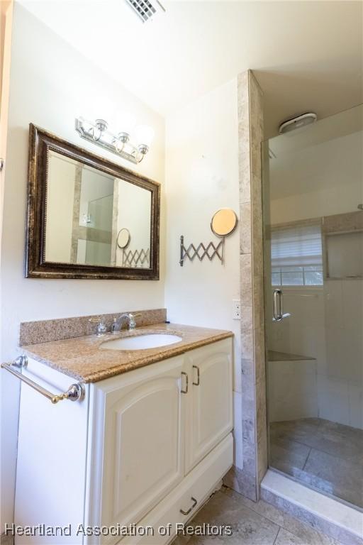 bathroom featuring a shower with shower door, vanity, and tile patterned floors