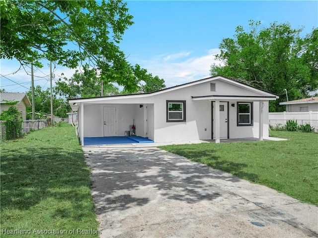 804 S 8th Ave, Wauchula, FL 33873 - view of front of house with fence, stucco siding, concrete driveway, a front lawn, and a carport