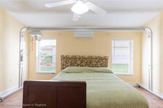 3108 Oakmont Dr, Avon Park, FL 33825 - bedroom with light wood finished floors, ceiling fan, an AC wall unit, and baseboards