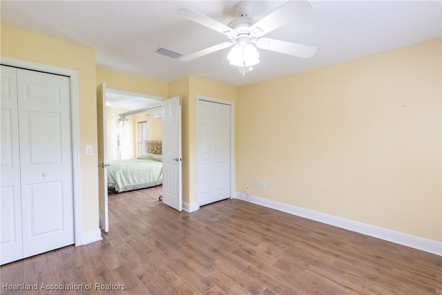 3108 Oakmont Dr, Avon Park, FL 33825 - unfurnished bedroom with two closets, a ceiling fan, visible vents, wood finished floors, and baseboards