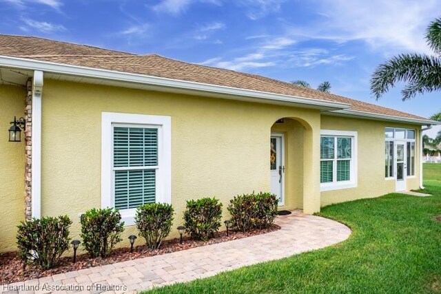 1624 Marble St, Sebring, FL 33870 - view of property exterior featuring stucco siding, a lawn, and a shingled roof