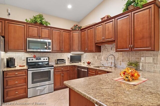 1624 Marble St, Sebring, FL 33870 - kitchen with appliances with stainless steel finishes, decorative backsplash, light tile patterned floors, lofted ceiling, and brown cabinets