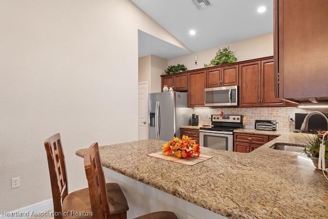 1624 Marble St, Sebring, FL 33870 - kitchen featuring appliances with stainless steel finishes, tasteful backsplash, a peninsula, light stone counters, and a kitchen bar