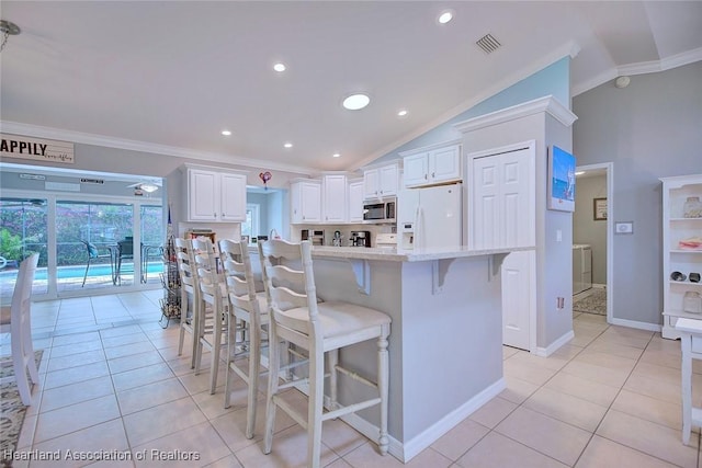 kitchen with white refrigerator with ice dispenser, crown molding, stainless steel microwave, visible vents, and independent washer and dryer