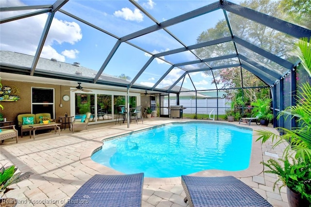 outdoor pool featuring glass enclosure, ceiling fan, a grill, a patio area, and outdoor lounge area