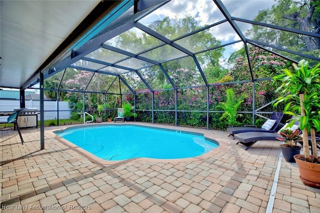 pool with a lanai, a patio area, fence, and grilling area