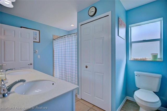 full bathroom with baseboards, toilet, a sink, tile patterned flooring, and a closet