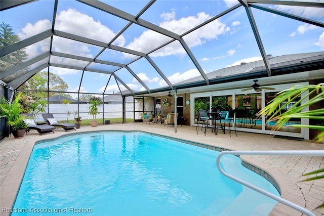 pool featuring a patio, glass enclosure, fence, and a ceiling fan