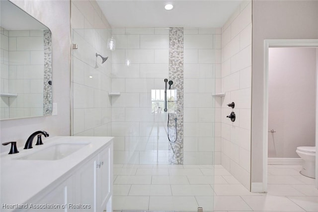 bathroom featuring toilet, tiled shower, and vanity