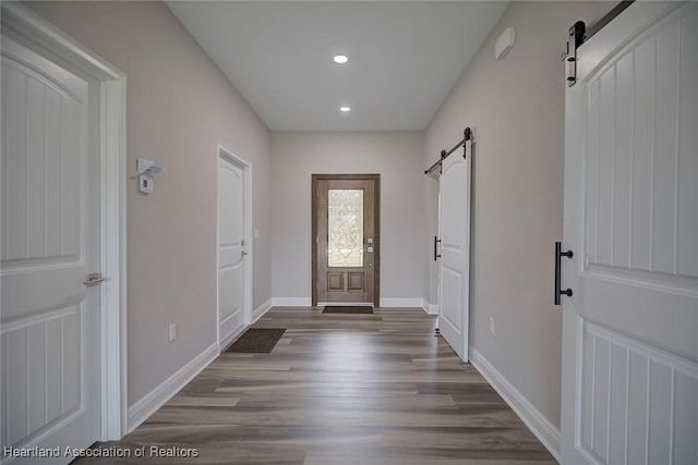 foyer entrance with a barn door and dark hardwood / wood-style flooring