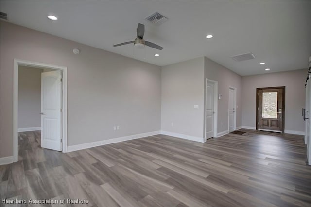 empty room featuring ceiling fan, a barn door, and light wood-type flooring