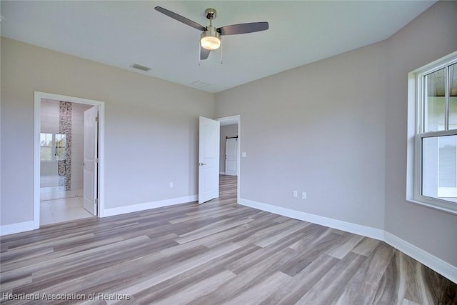 unfurnished bedroom featuring light hardwood / wood-style flooring, ensuite bath, and ceiling fan