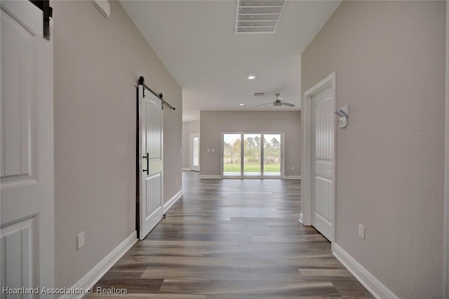 hall featuring dark wood-type flooring and a barn door