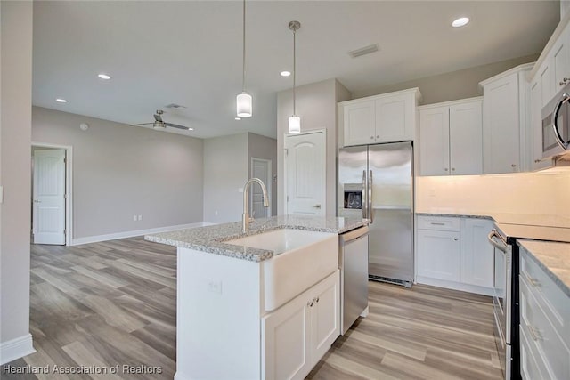 kitchen with white cabinets, appliances with stainless steel finishes, sink, and an island with sink