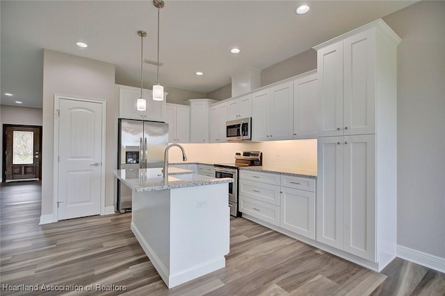 kitchen with light stone countertops, white cabinetry, light hardwood / wood-style flooring, and appliances with stainless steel finishes