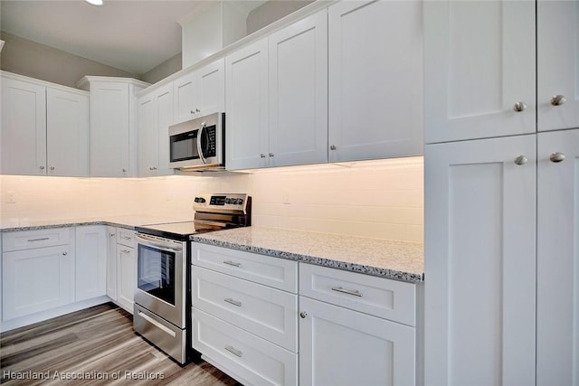 kitchen featuring white cabinets, stainless steel appliances, light hardwood / wood-style flooring, and backsplash