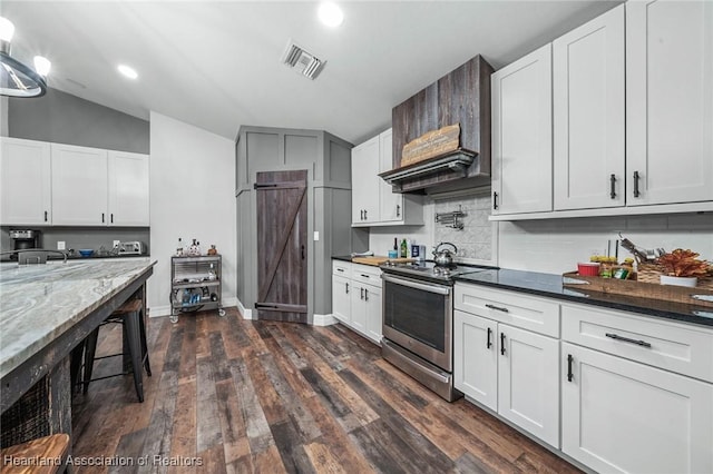 kitchen with visible vents, decorative backsplash, dark wood finished floors, dark stone countertops, and stainless steel range with electric cooktop