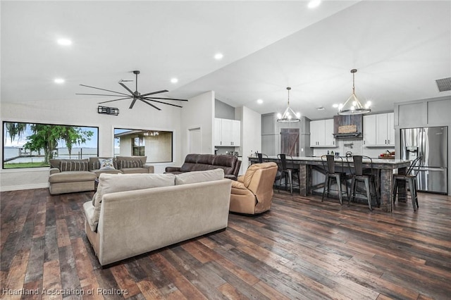 living area featuring lofted ceiling, dark wood-style floors, visible vents, and an inviting chandelier