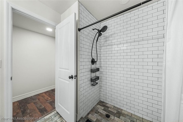 bathroom with baseboards, tiled shower, and wood finished floors