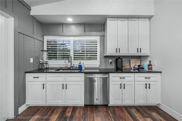 kitchen with dark countertops, dark wood finished floors, a sink, and stainless steel dishwasher