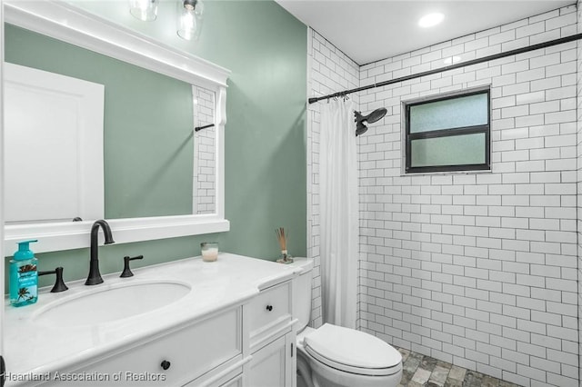 bathroom with a tile shower, vanity, and toilet