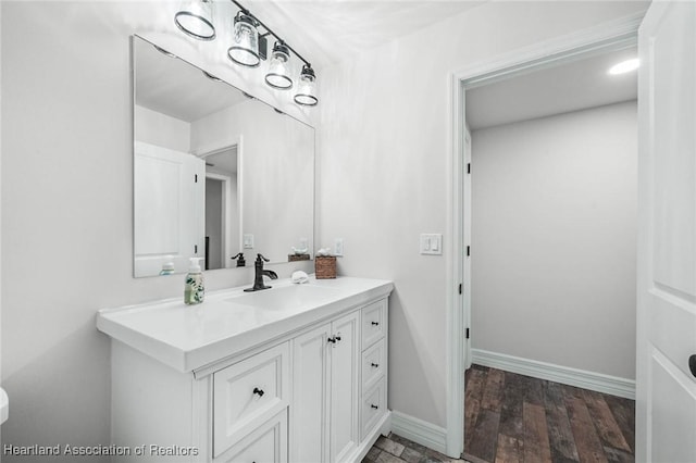 bathroom with baseboards, wood finished floors, and vanity