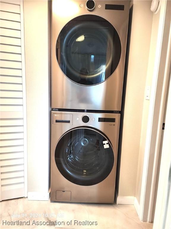 washroom with stacked washer / dryer and light tile patterned flooring