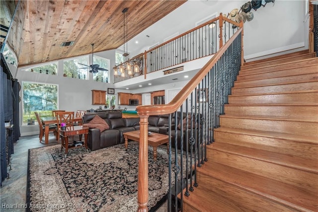 living room with a high ceiling, ceiling fan, and wood ceiling