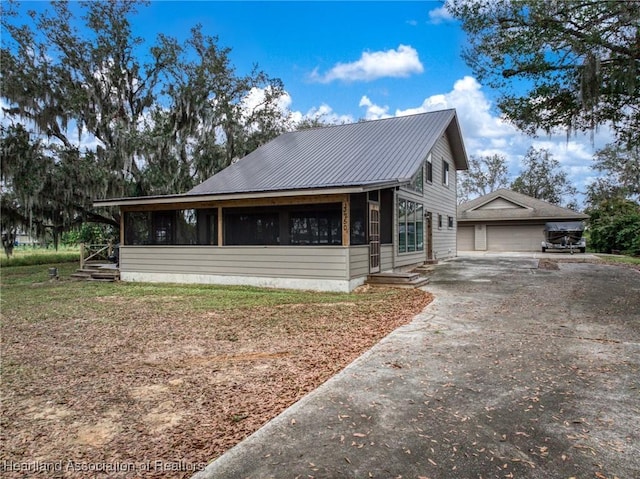 bungalow-style home with a sunroom, an outbuilding, and a garage