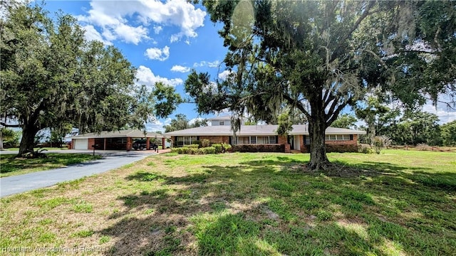 ranch-style house featuring a front lawn, driveway, and brick siding
